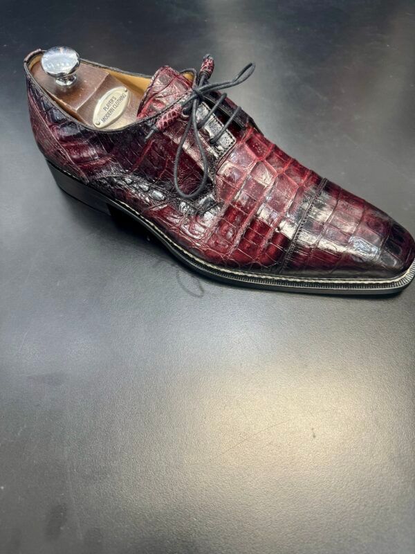 A pair of red shoes is sitting on a black surface.