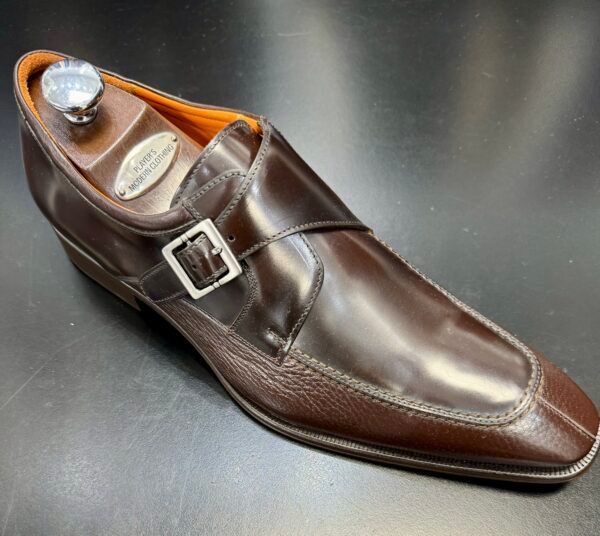 A pair of brown shoes with a buckle on the side