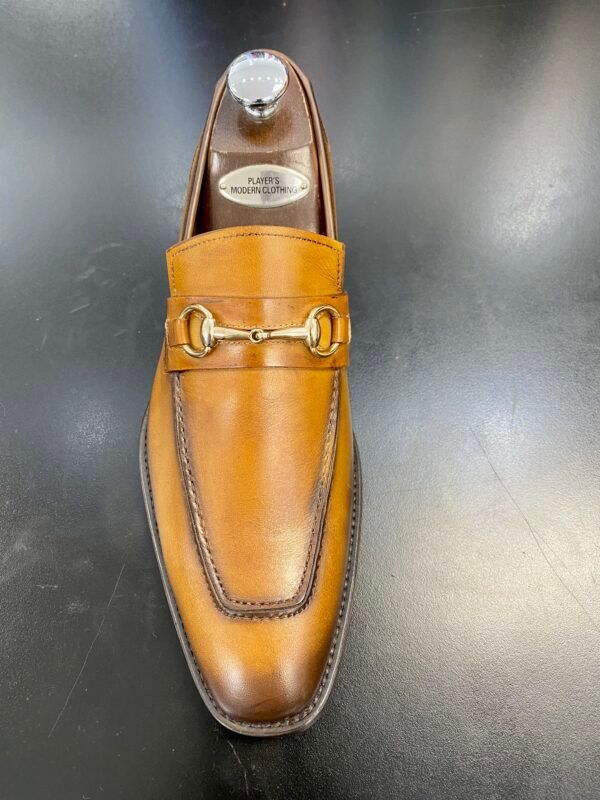 A pair of brown loafers with a gold buckle