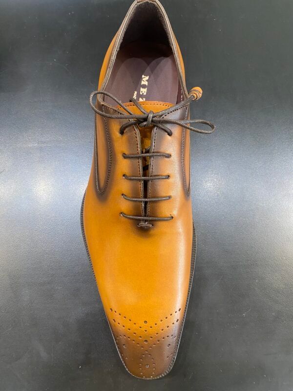 A pair of brown shoes with brown laces on a black surface