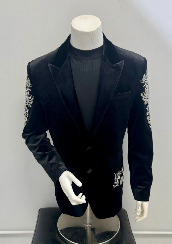 A black jacket with white embroidery on the sleeves is on a mannequin.