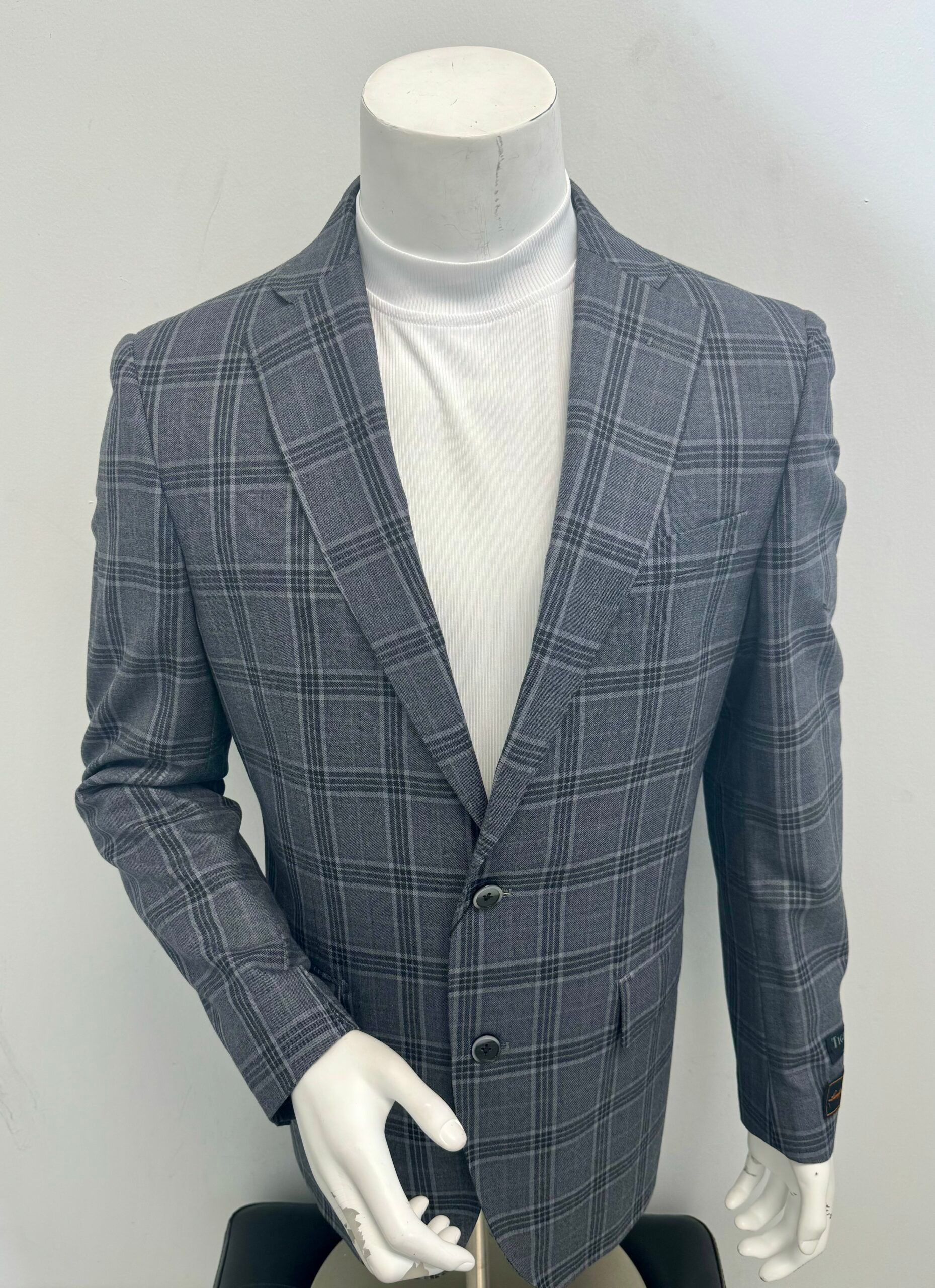 A mannequin is wearing a gray plaid jacket and a white turtleneck.