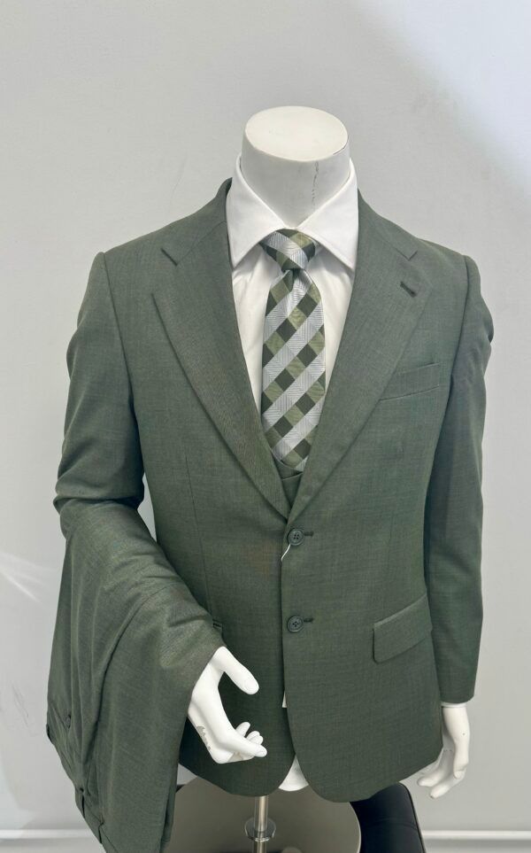 A mannequin is wearing a green suit and tie.