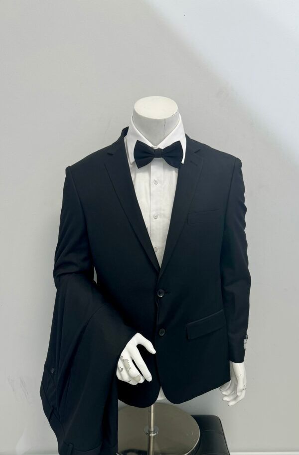 A mannequin is wearing a black tuxedo and bow tie.