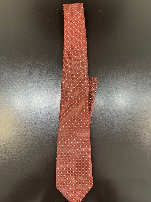 A red tie with white polka dots is on a black surface
