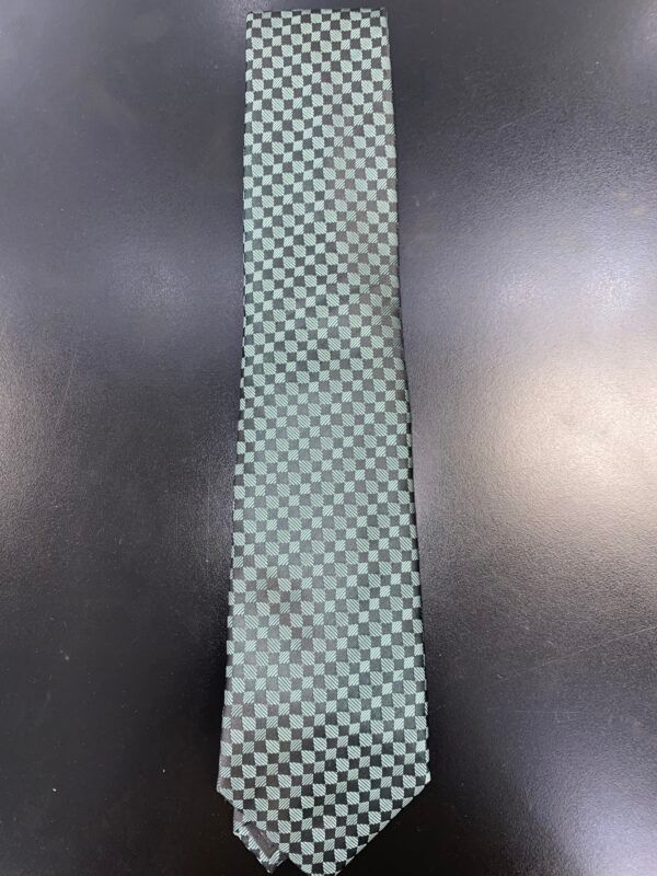 A green and black checkered tie is sitting on a black table.