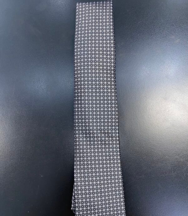 A black and white tie is sitting on a black table.