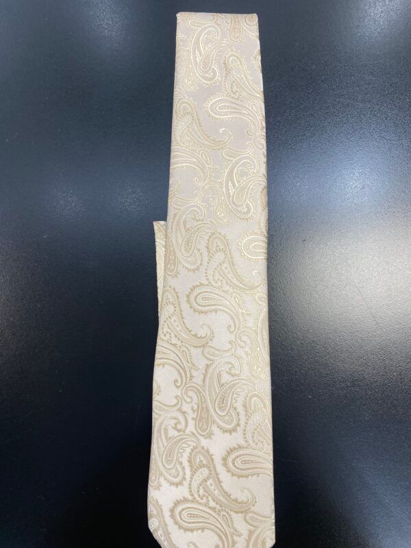 A white tie with a paisley pattern is sitting on a black table.