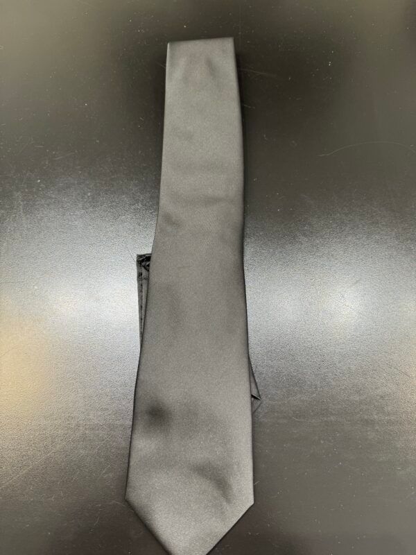 A black tie is sitting on a black table.