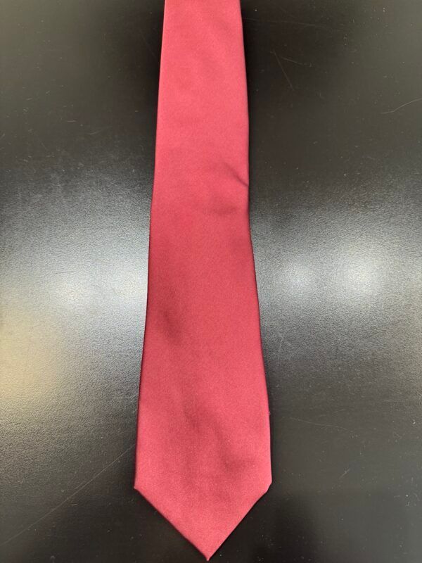 A red tie is sitting on a black table.