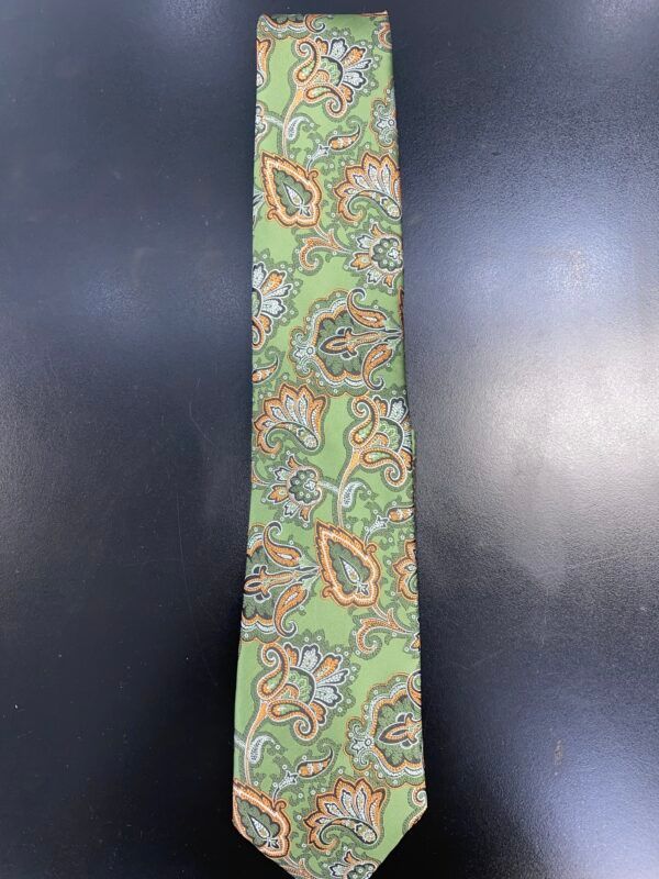 A green paisley tie is sitting on a black table.