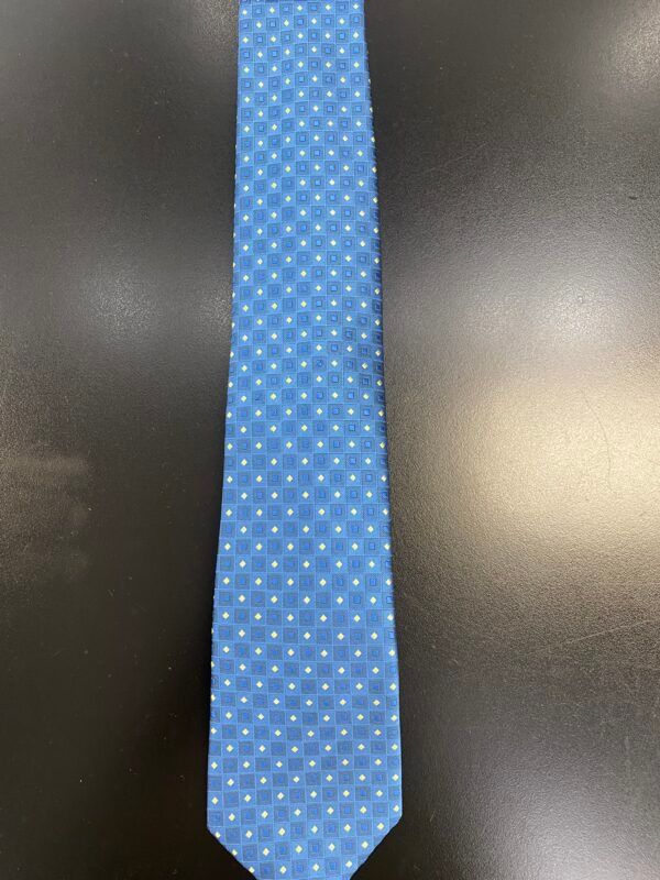 A light blue tie with white polka dots is sitting on a black table.