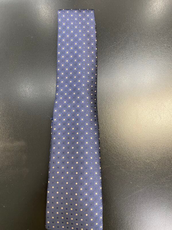 A blue tie with white polka dots is sitting on a black table.