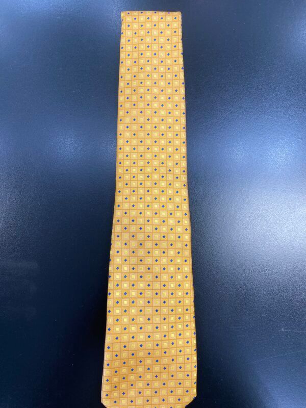 A yellow tie with blue polka dots is sitting on a black table.
