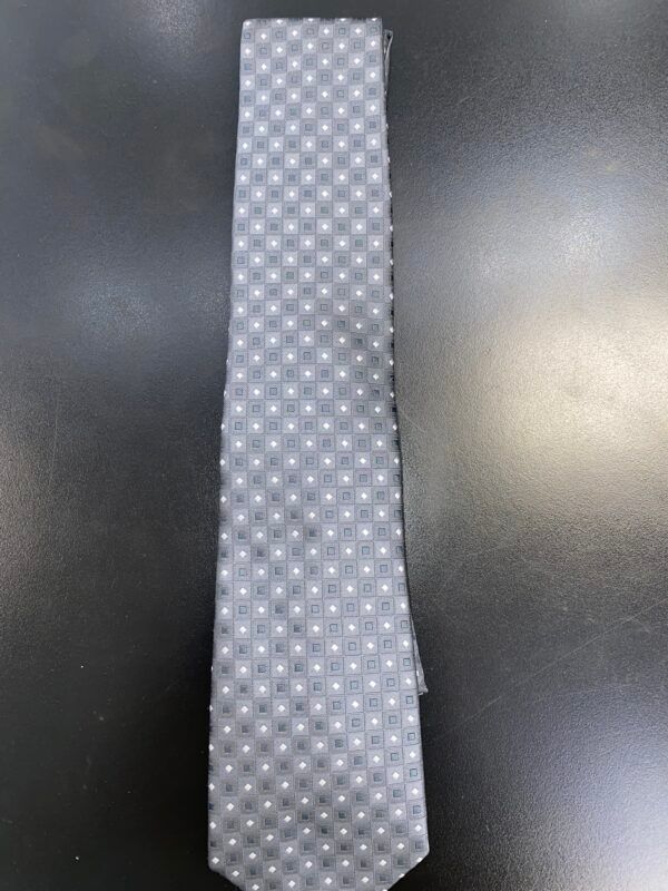 A white tie with black polka dots is sitting on a black table.
