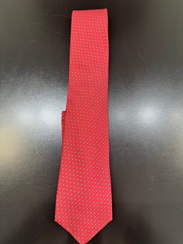 A red tie with white polka dots is sitting on a black table.