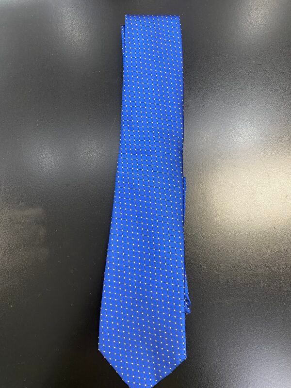 A blue tie with white polka dots is sitting on a black table.