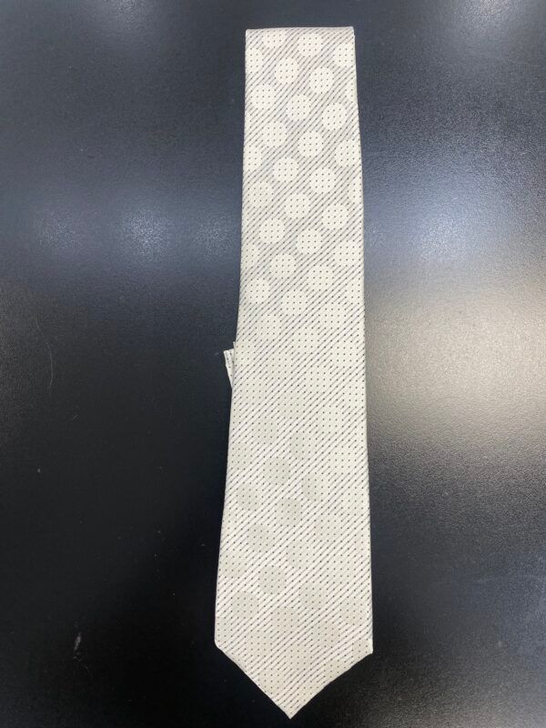 A white tie with polka dots on it is on a black surface
