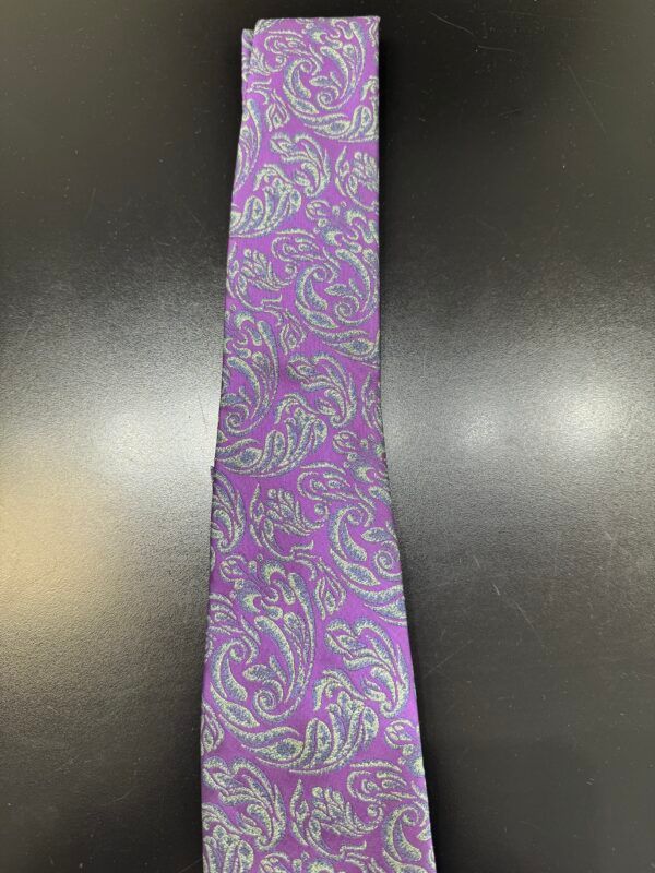 A purple tie with a paisley pattern is sitting on a black table.