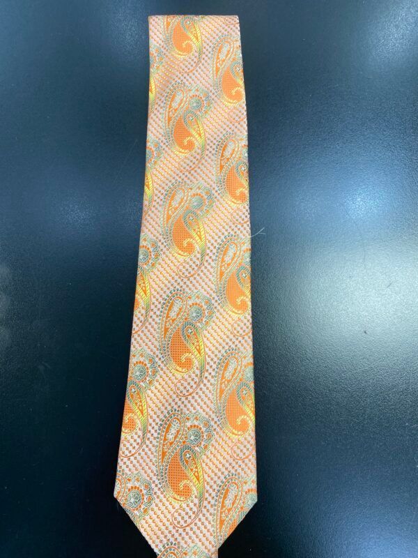 A tie with a paisley pattern is sitting on a black table.