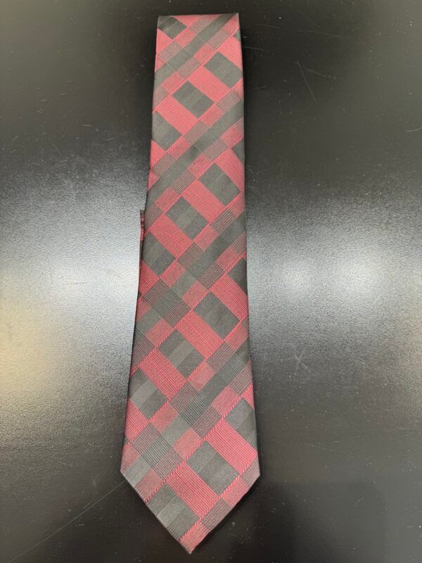 A red and black tie is sitting on a black table.