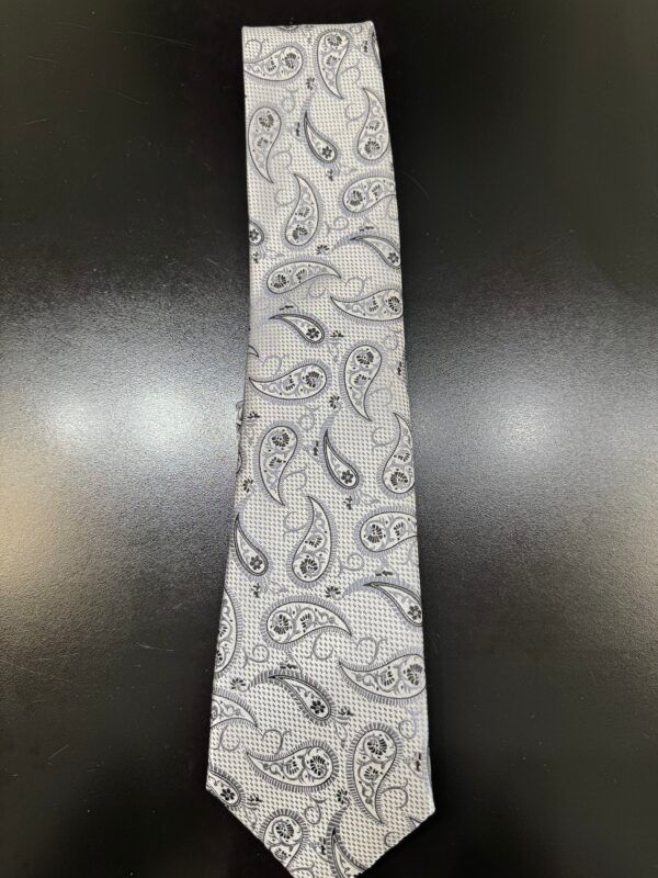 A white tie with a paisley pattern is sitting on a black table.