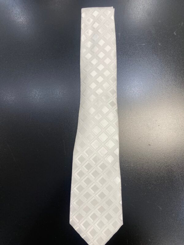 A white tie with squares on it is on a black surface.