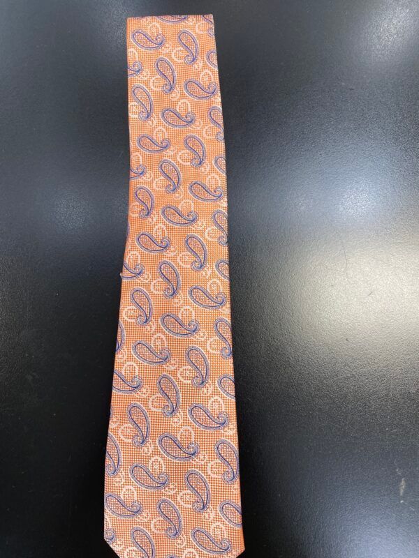 An orange tie with a paisley pattern on it