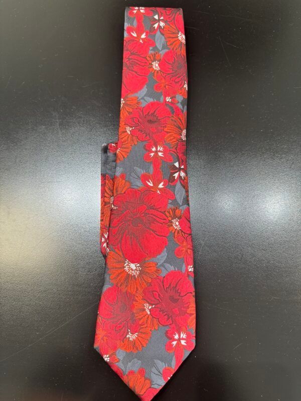 A red tie with flowers on it is on a black table
