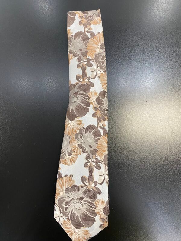 A brown and white floral tie is on a black surface