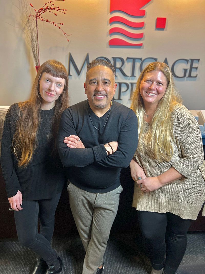 Three people pose in front of a Mortgage Partners logo. The central person has arms crossed. All are smiling.
