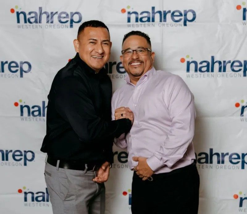 Two men shaking hands in front of a backdrop with the 