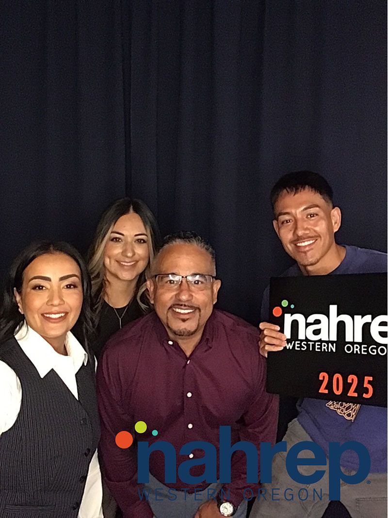 Four people smiling, posing in front of a blue backdrop, holding a sign for Nahrep Western Oregon 2025.