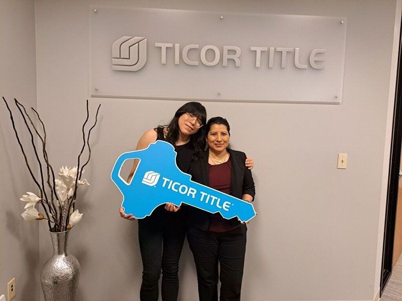 Two people holding a large blue key in front of a 