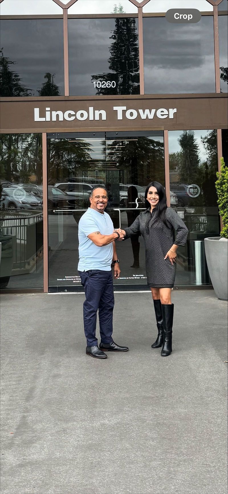 Two people shaking hands in front of Lincoln Tower building.
