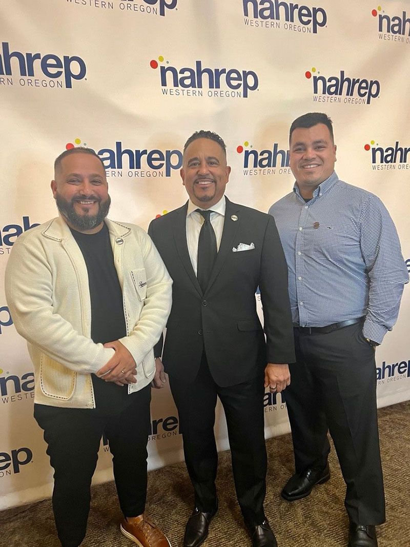 Three men posing in front of a backdrop with the word 