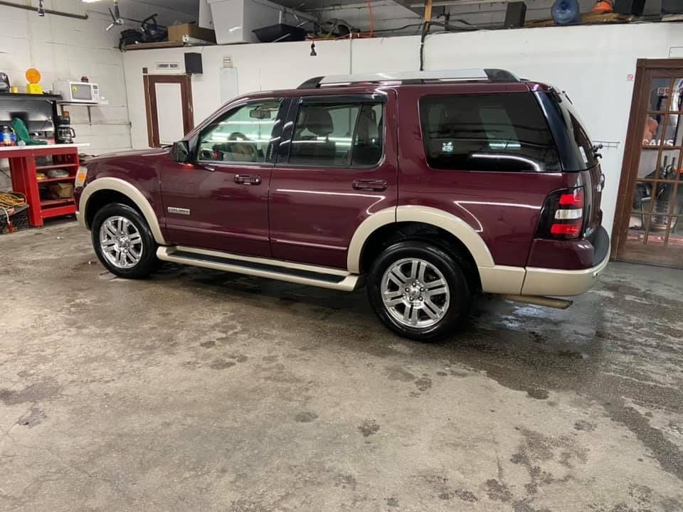 Burgundy Ford Explorer SUV in a garage, with tan accents, parked on a concrete floor.