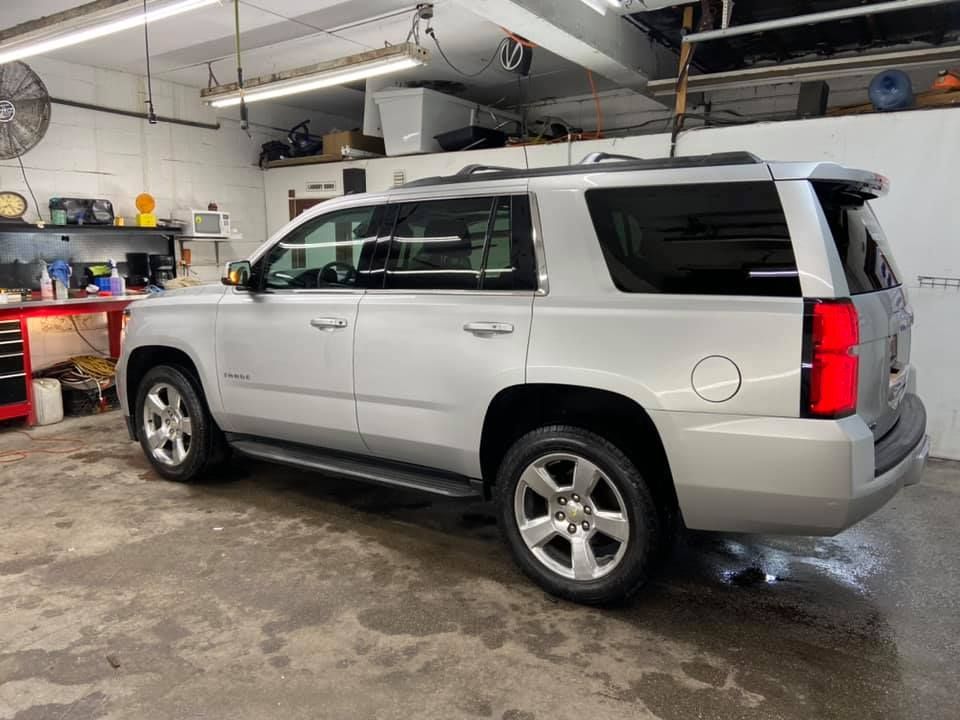 Silver SUV parked inside a garage; tail lights are on.