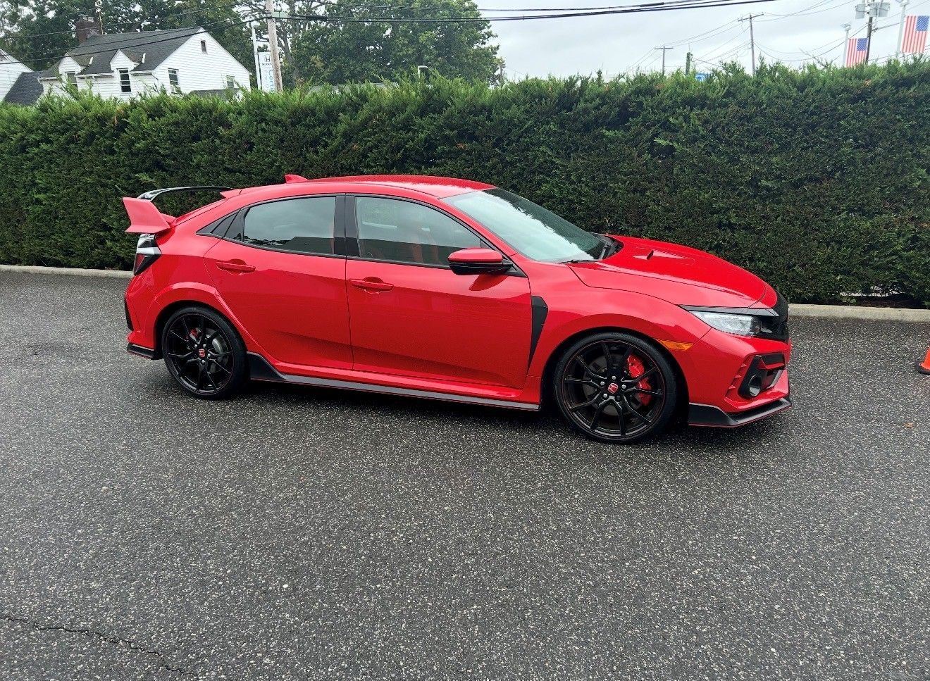 Red Honda Civic Type R parked on wet pavement.