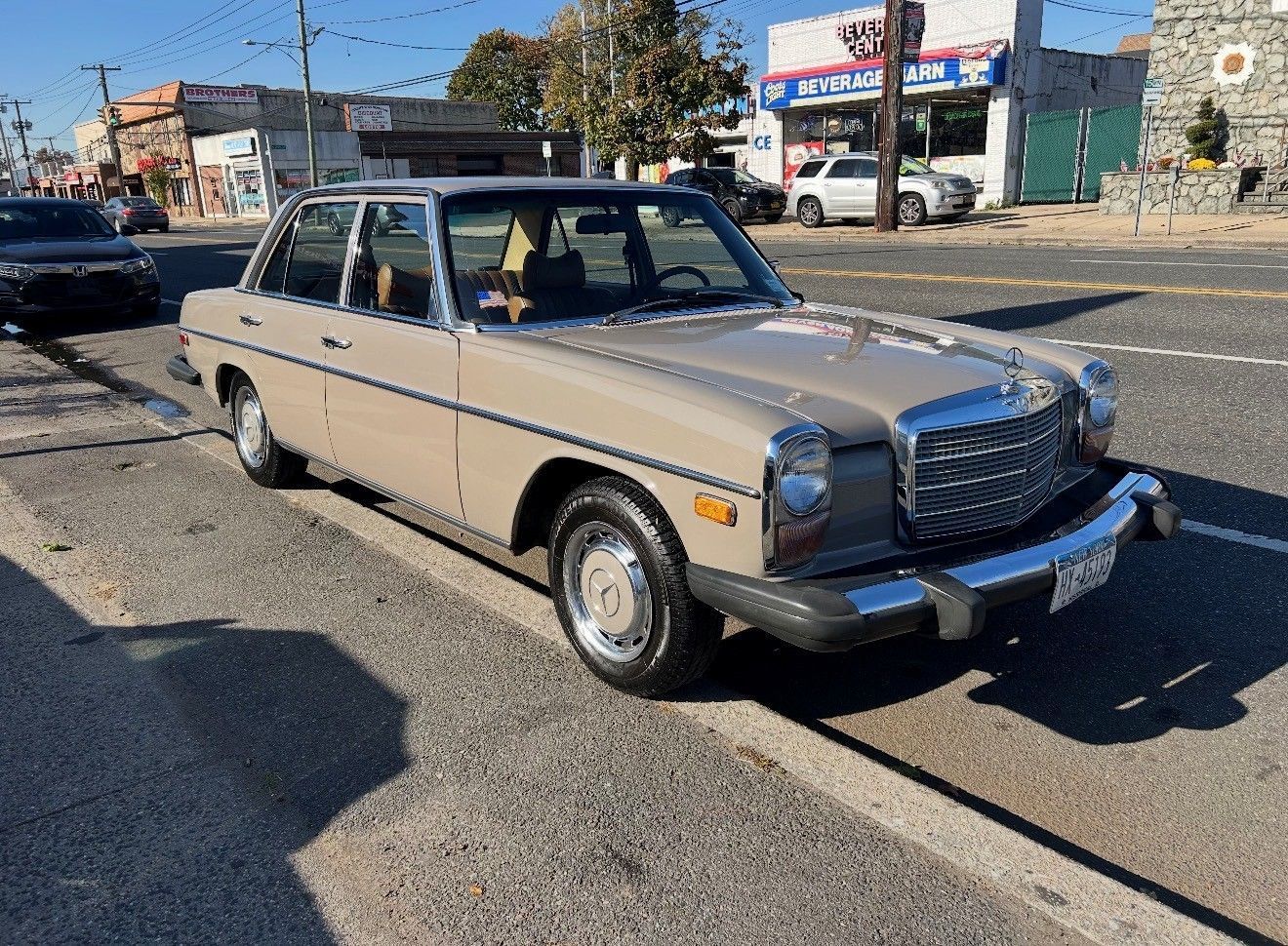 Tan Mercedes-Benz sedan parked on the side of a city street.