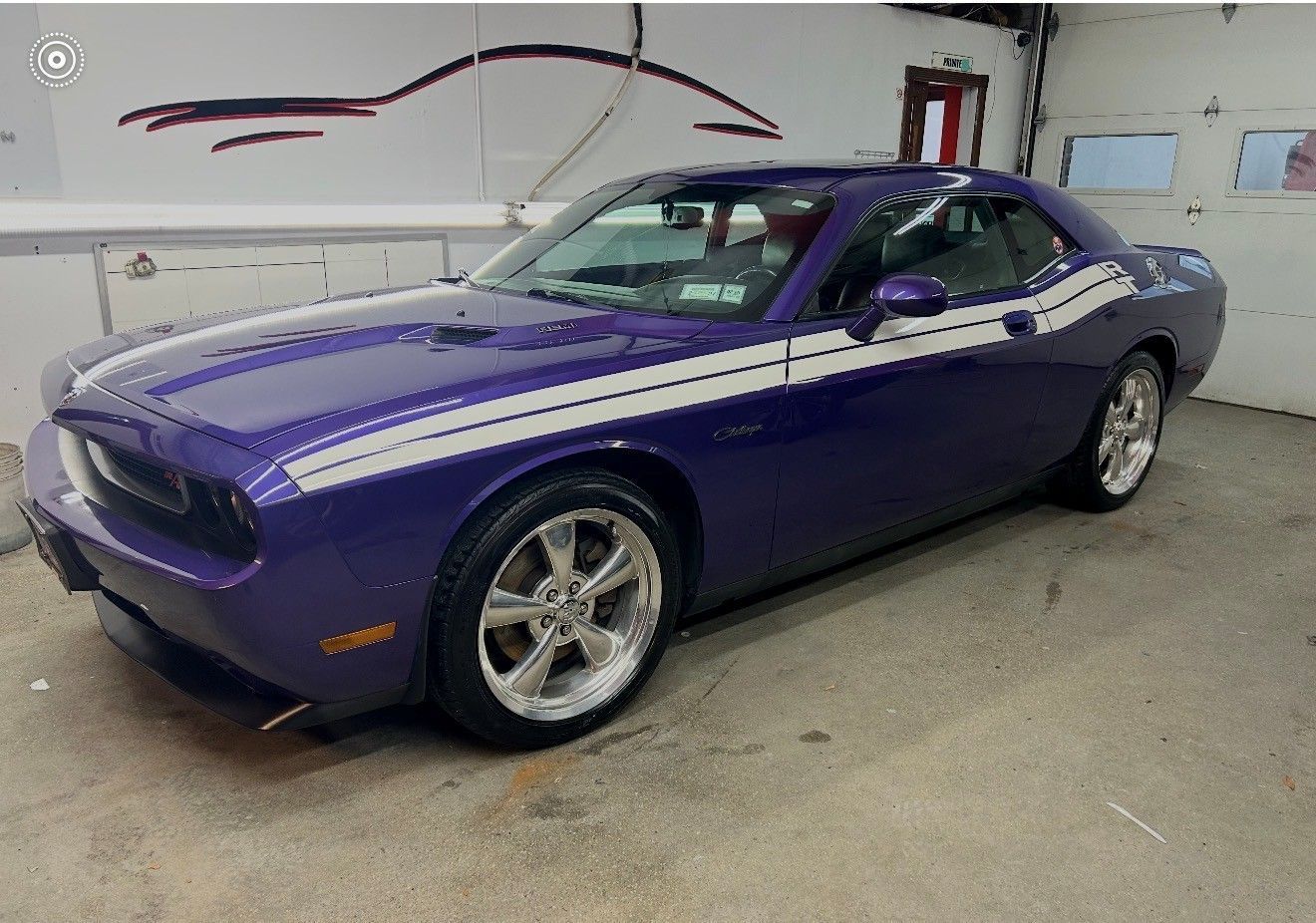 Purple Dodge Challenger with white stripes, parked in a garage.