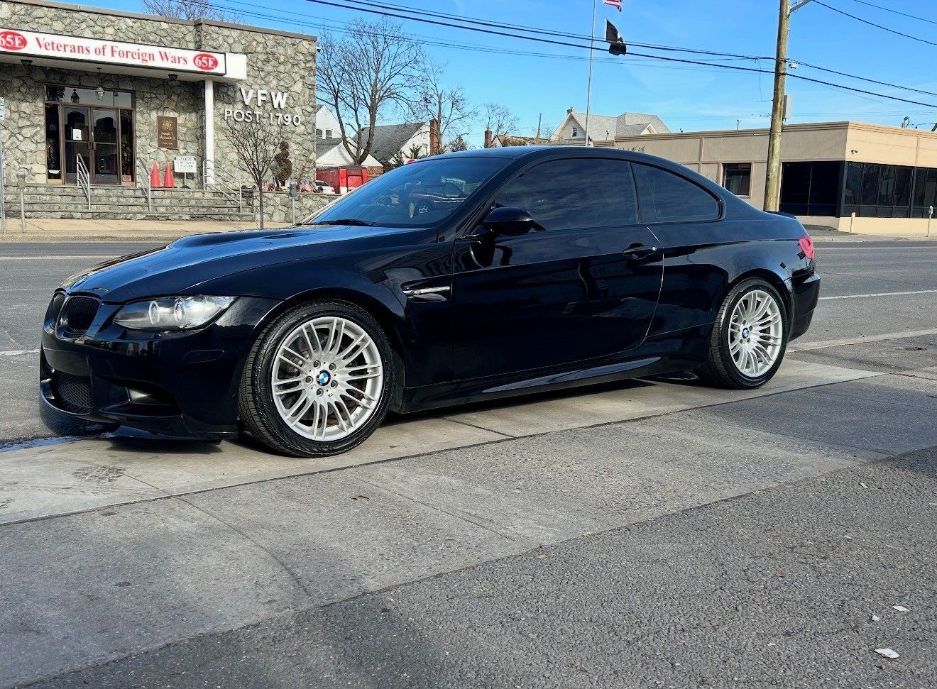 Black BMW M3 coupe parked on a city street, with tinted windows and silver wheels.
