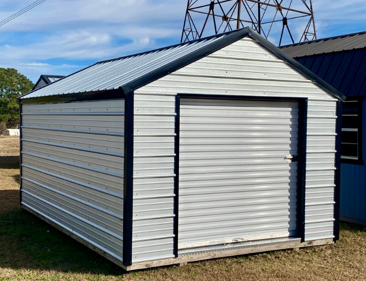Metal storage shed with a roll-up door, silver siding, and dark trim, outdoors.