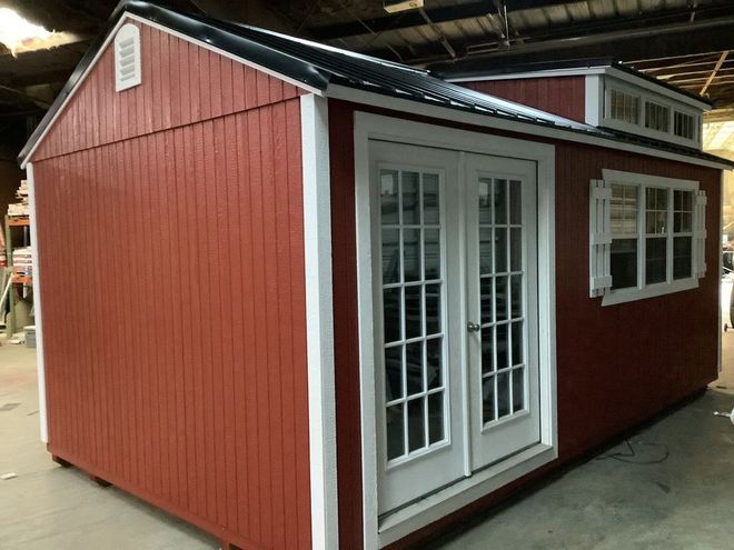 Red shed with white trim, French doors, and small windows.