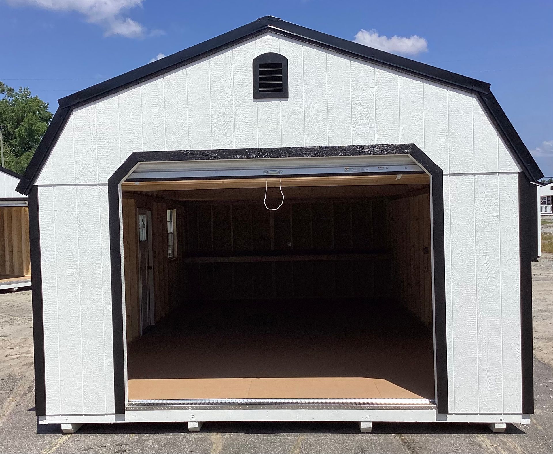 White shed with open garage door; black trim and roof.