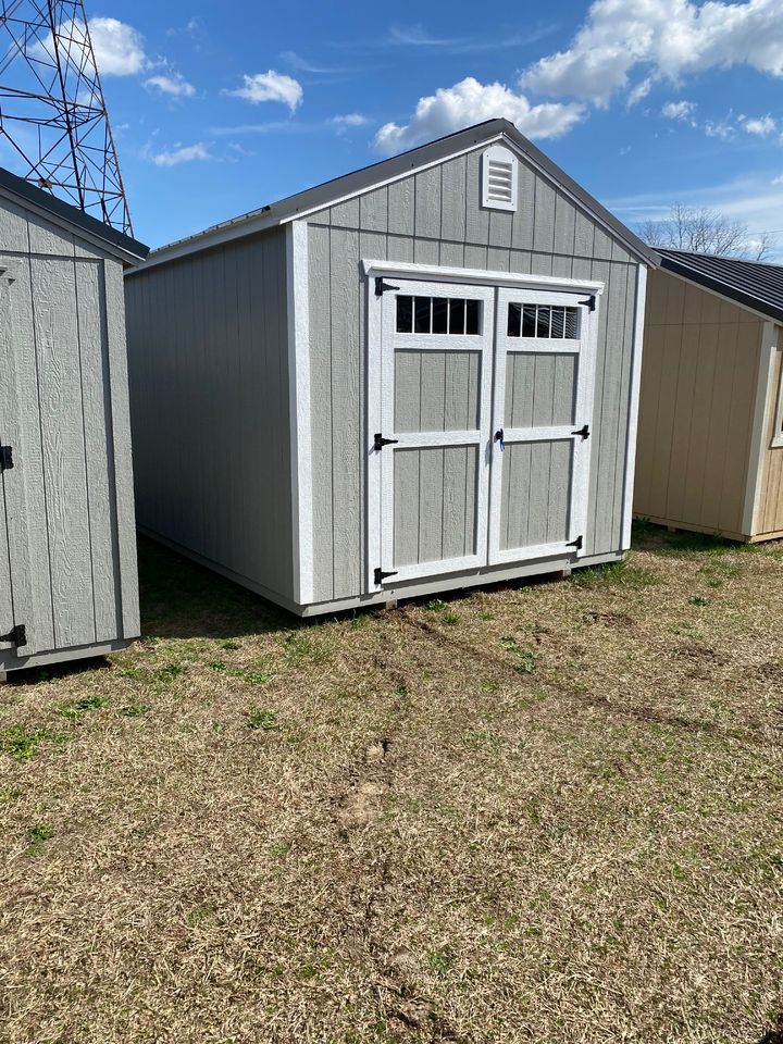 Gray storage shed with double doors, white trim, and a small vent.