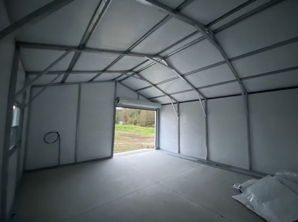 Interior of a metal framed structure, possibly a shed or workshop, with a doorway and white walls.