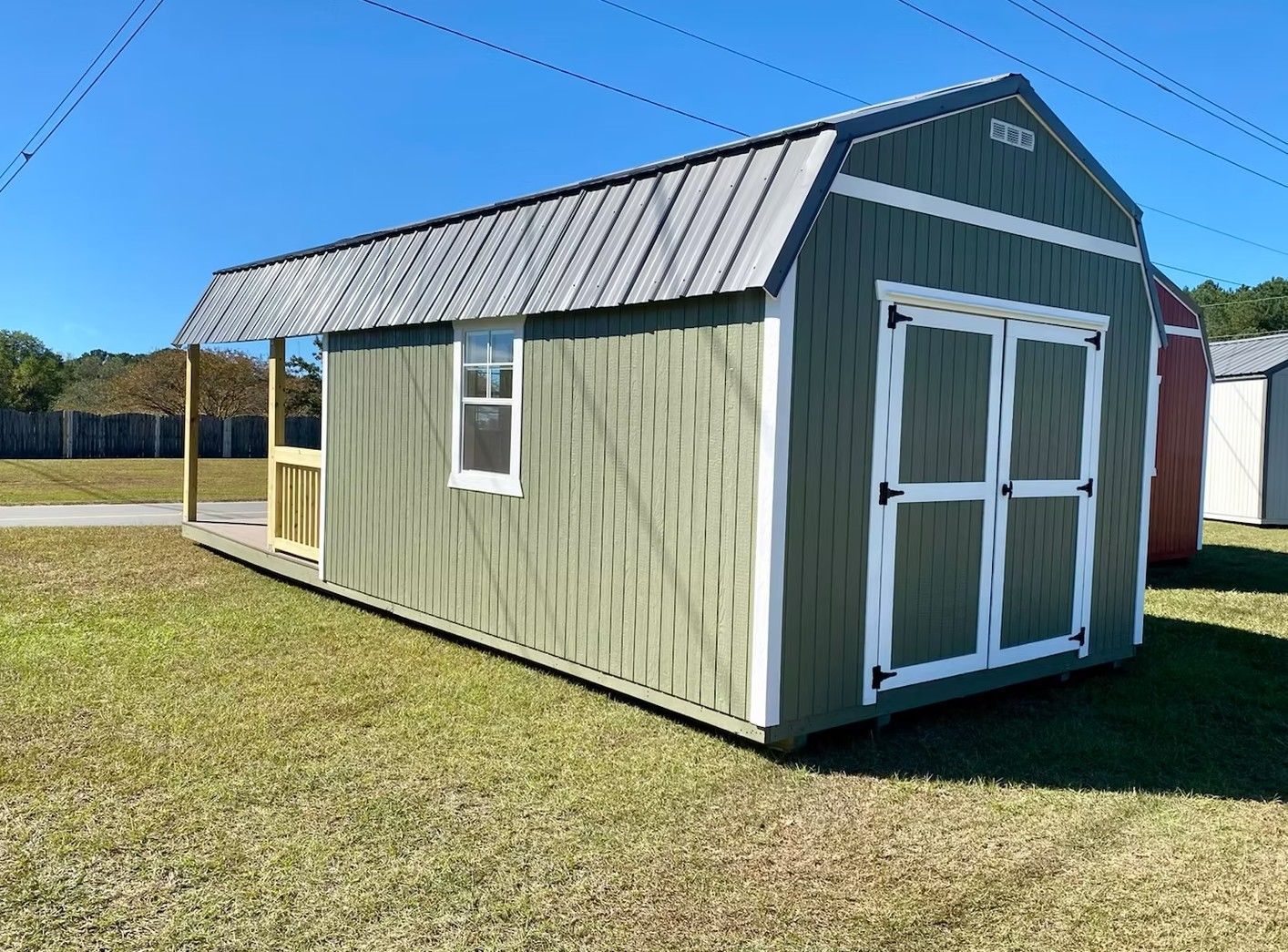 Green storage shed with gray roof, white trim, and small porch.
