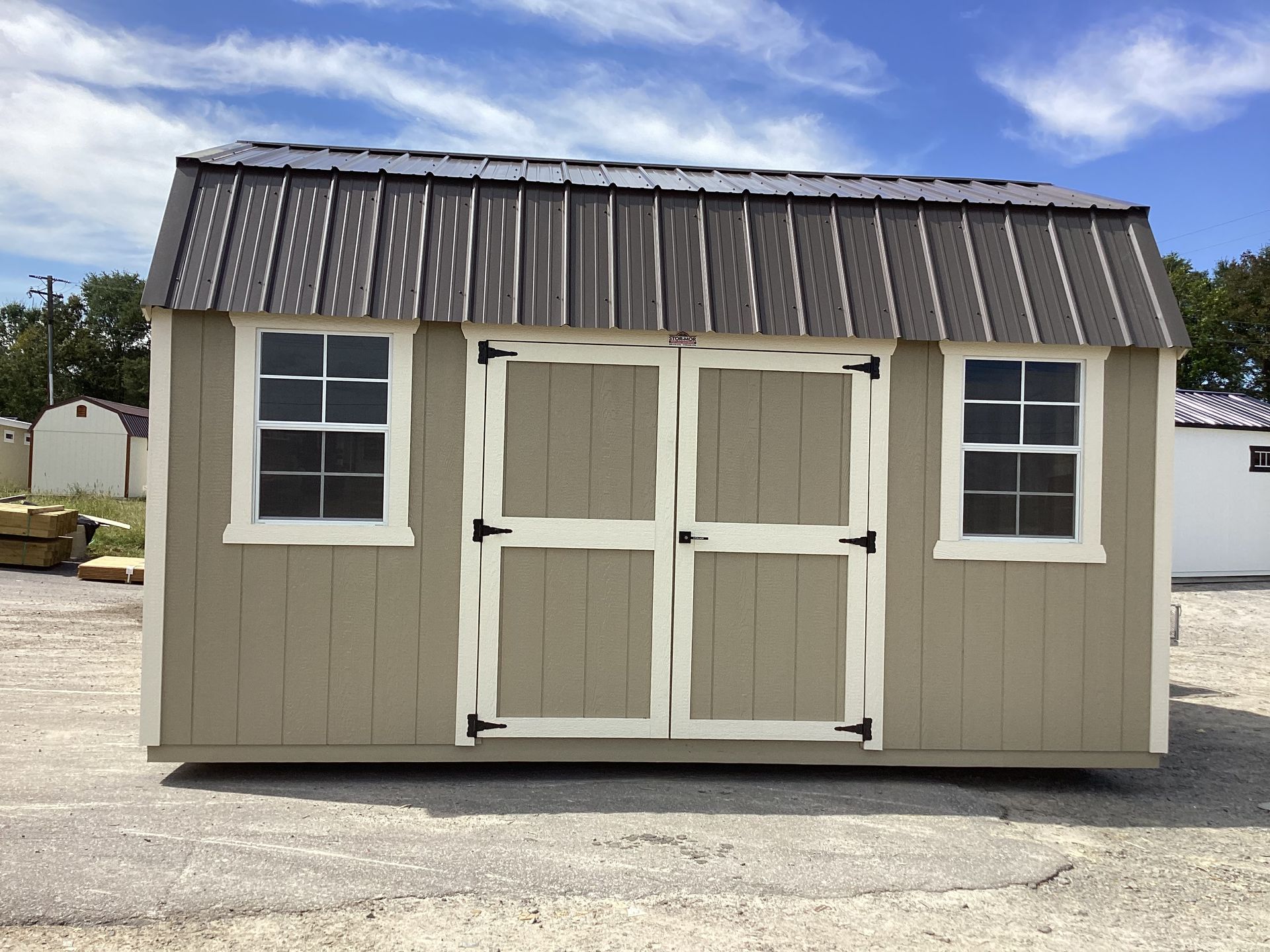 Tan shed with metal roof, two windows, and double doors.