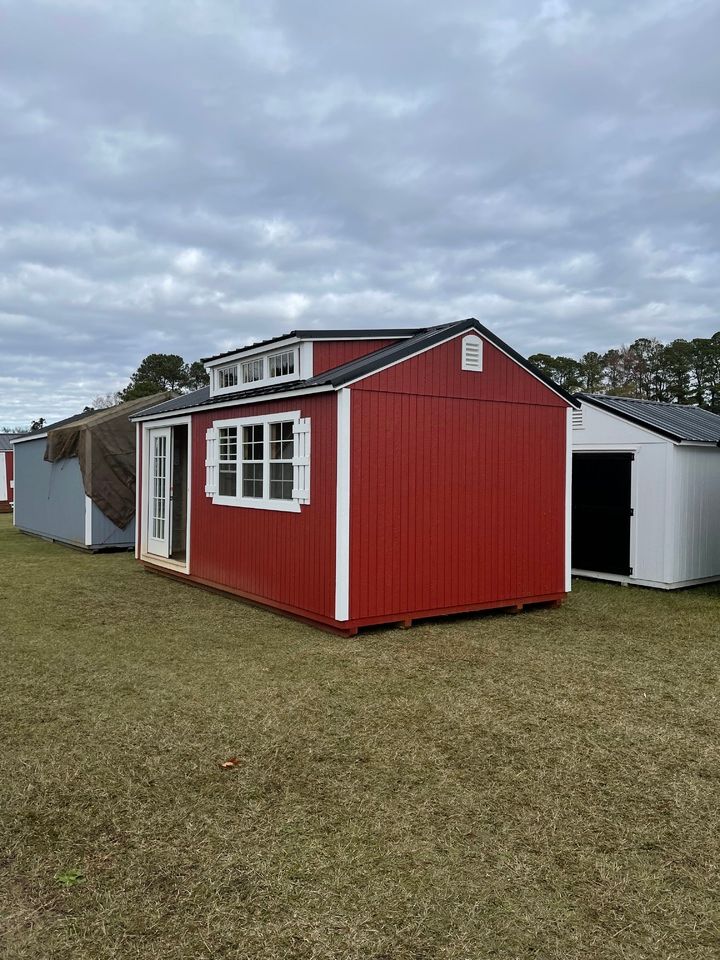 Red shed with white trim, double doors, and a small loft window, set on grass.